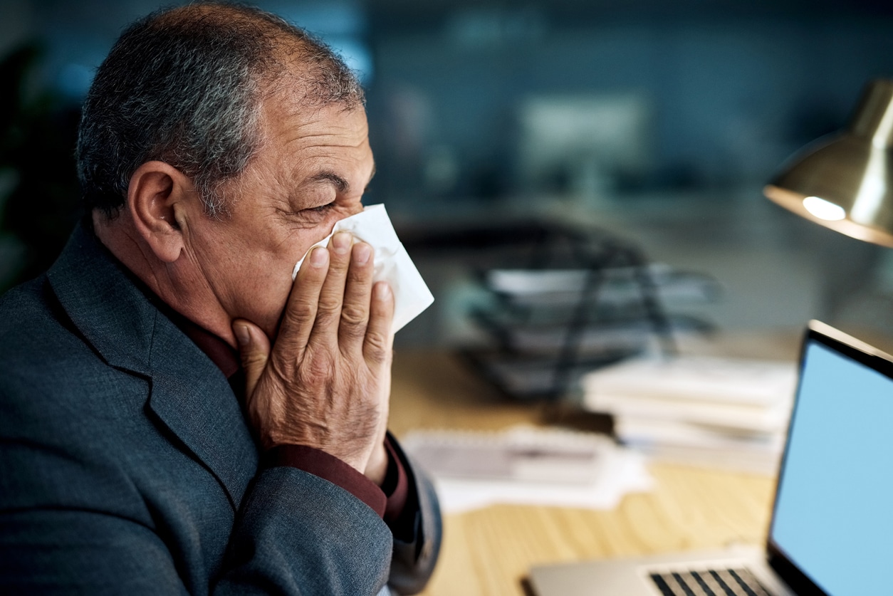 man blowing his nose into a tissue due to nasal obstruction