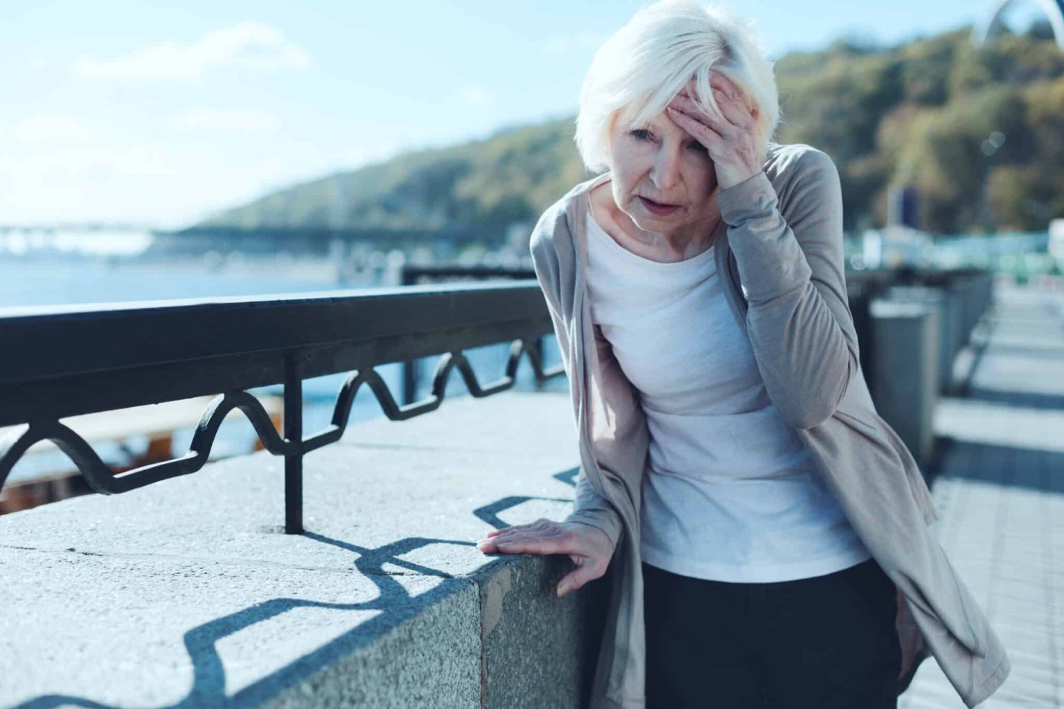 Woman with hearing loss having a dizzy spell outside.