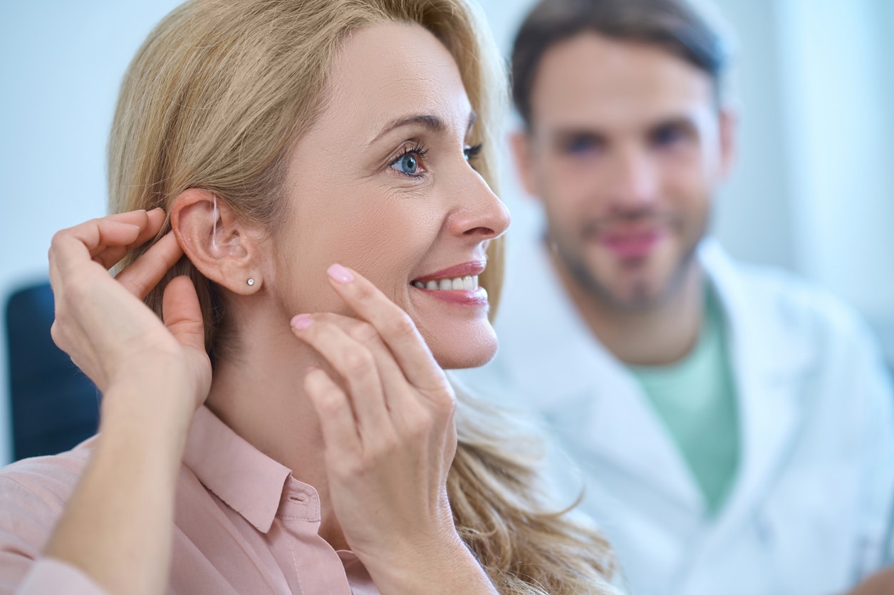 Woman touches hearing aid