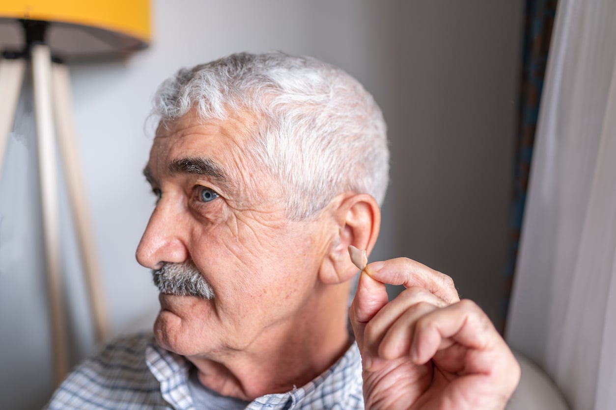 Senior man showing his in-the-canal hearing aid.