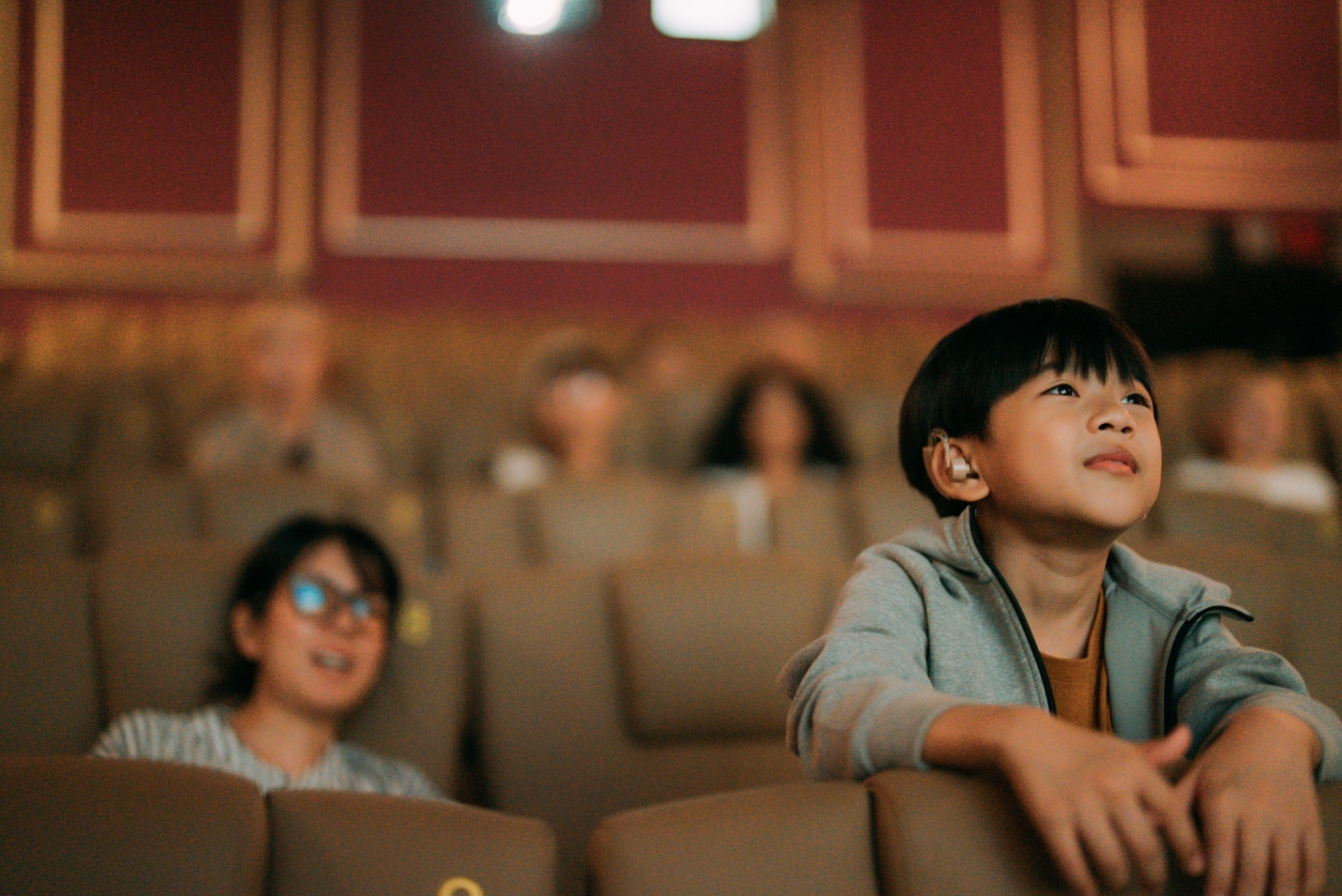 Boy with hearing aids watches movie