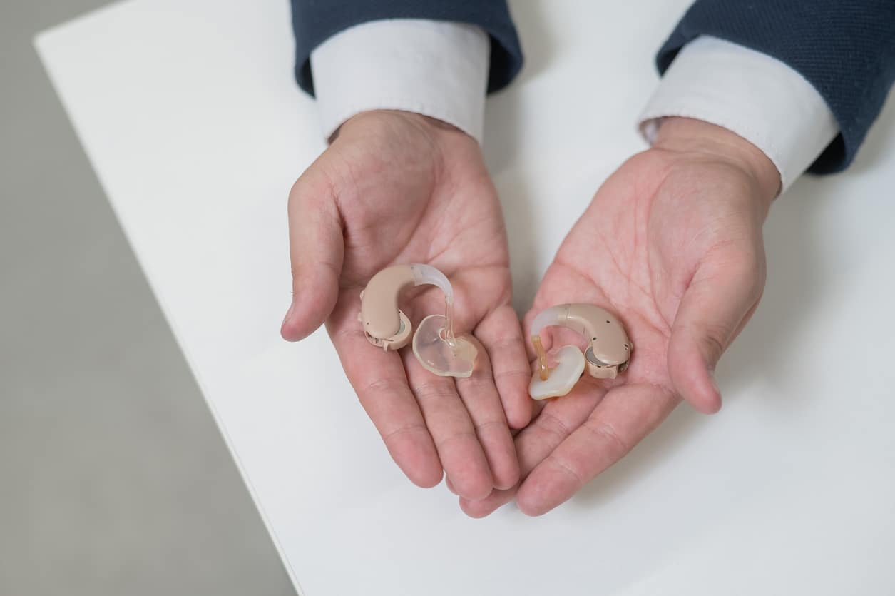 Two hands holding hearing aids.