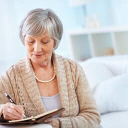 Senior woman writing her new year's resolutions in a journal