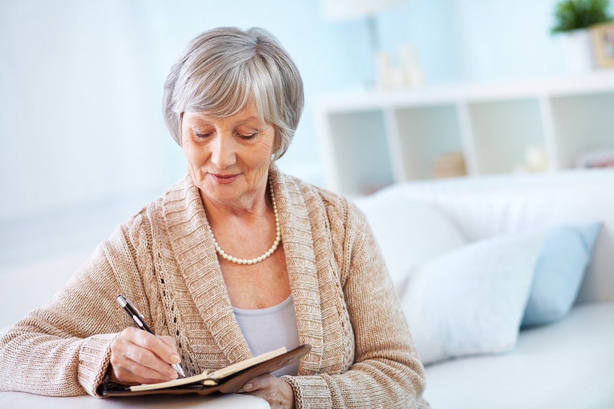 Senior woman writing her new year's resolutions in a journal.