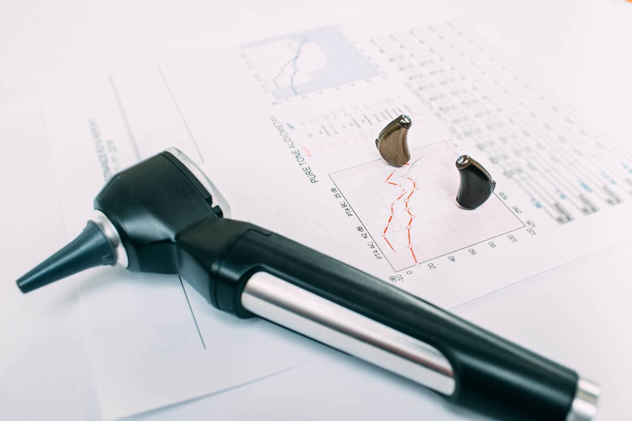 Hearing exam result - audiogram and hearing aids on the table.