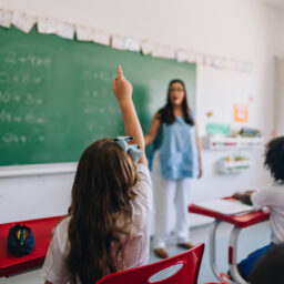ear view of a girl student raising her hand to ask on classroom at school
